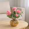 Pink artificial roses in a gold porcelain pot
